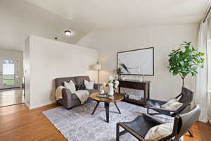 Living room with wood finished floors, lofted ceiling, and baseboards