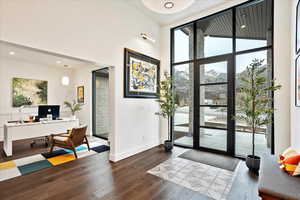 Doorway with a towering ceiling, baseboards, wood finished floors, and recessed lighting