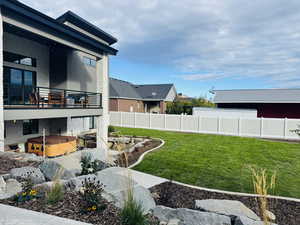 Fenced backyard featuring a hot tub, balcony and completed landscaping.