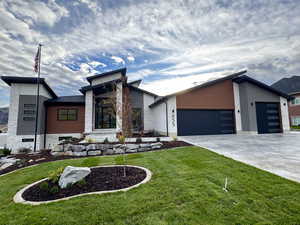Modern home featuring an attached garage, new landscaping, and concrete driveway