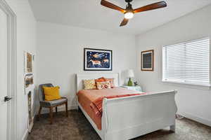 Bedroom featuring ceiling fan, baseboards, and dark colored carpet