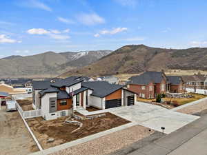 View of front of property with a residential view, a mountain view, driveway, fence, and a shingled roof