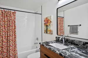 Full bathroom with shower / tub combo with curtain, vanity, and toilet