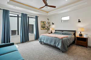 Carpeted bedroom featuring ceiling fan, baseboards, ornamental molding, and a raised ceiling