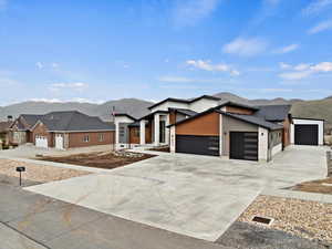 View of front of property with concrete driveway, an attached garage, and a mountain view