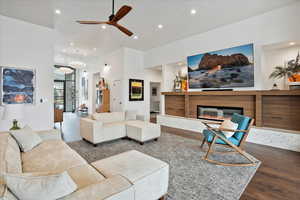 Living area featuring a glass covered fireplace, a ceiling fan, wood finished floors, and recessed lighting