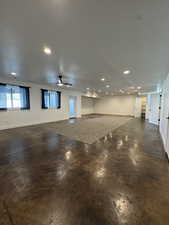 Basement living room featuring concrete floors, recessed lighting, baseboards, a textured ceiling, and a ceiling fan