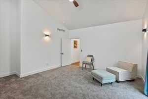 Living area with carpet floors, visible vents, a ceiling fan, and high vaulted ceiling