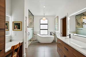 Bathroom featuring a soaking tub, a textured ceiling, tile walls, a shower stall, and vanity
