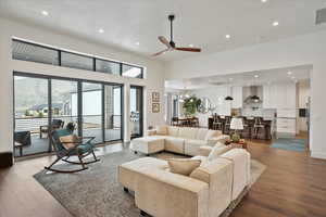 Living room featuring a towering ceiling, a ceiling fan, wood finished floors, and recessed lighting
