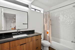 Full bath featuring shower / tub combo with curtain, toilet, and vanity