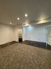 Finished below grade area with recessed lighting, dark carpet, and baseboards
