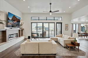 Living area featuring recessed lighting, a glass covered fireplace, a towering ceiling, and ceiling fan with notable chandelier