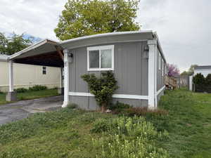 View of side of home with an attached carport, fence, a yard, and driveway