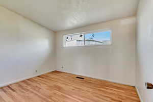 Spare room with baseboards, wood finished floors, and visible vents