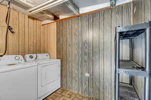 Washroom featuring wooden walls, separate washer and dryer, and laundry area