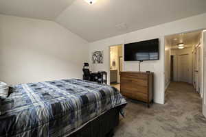 Bedroom with visible vents, vaulted ceiling, carpet floors, and connected bathroom