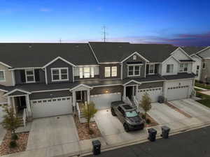 Townhome / multi-family property featuring board and batten siding, a shingled roof, driveway, and a garage