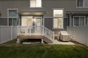 Rear view of house featuring stucco siding, a lawn, and fence