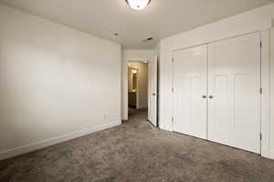 Unfurnished bedroom featuring a closet, carpet floors, visible vents, and baseboards