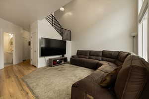 Living room featuring light wood finished floors, baseboards, and a towering ceiling