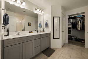 Bathroom featuring tile patterned floors, visible vents, a sink, and double vanity