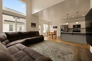 Living area featuring light wood-type flooring, a towering ceiling, recessed lighting, and a chandelier