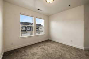 Carpeted empty room with baseboards and visible vents