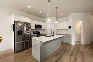 Kitchen featuring light wood finished floors, stainless steel appliances, baseboards, and a sink