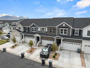 Multi unit property with an attached garage, a residential view, a mountain view, and concrete driveway
