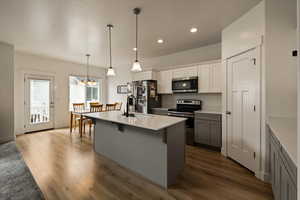 Kitchen with dark wood finished floors, a sink, a kitchen bar, appliances with stainless steel finishes, and a notable chandelier