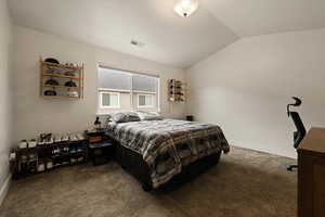 Carpeted bedroom featuring lofted ceiling, visible vents, and baseboards