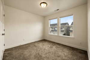Carpeted empty room with baseboards and visible vents