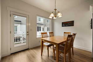 Dining space with baseboards, a chandelier, and light wood-type flooring