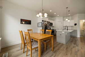 Dining area with recessed lighting, visible vents, light wood-type flooring, baseboards, and a chandelier