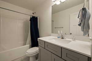 Full bathroom with toilet, vanity, tile patterned floors, and shower / bathtub combination with curtain