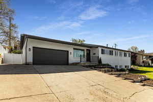 View of front facade featuring concrete driveway, brick siding, fence, and a garage
