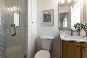 Bathroom with vanity, toilet, and a stall shower