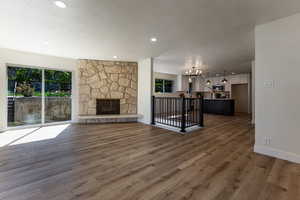 Unfurnished living room featuring baseboards, wood finished floors, a textured ceiling, and a notable chandelier