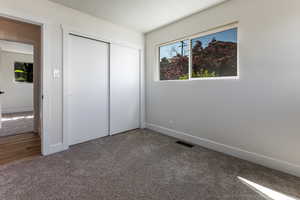 Unfurnished bedroom featuring a closet, carpet, visible vents, and baseboards