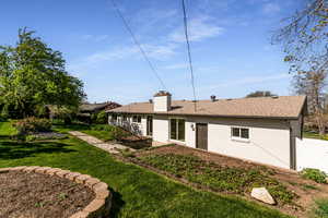 Back of property with a lawn, a chimney, a shingled roof, fence, and brick siding