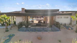 Back of house with stucco siding, stone siding, fence, and a patio area
