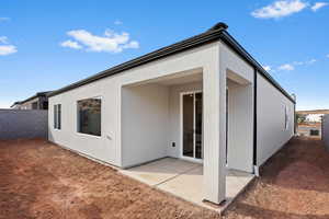 Rear view of house featuring fence, stucco siding, and a patio