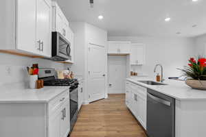 Kitchen featuring stainless steel appliances, light wood-style flooring, a sink, and recessed lighting