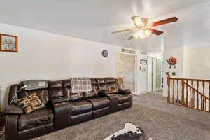 Carpeted living room featuring visible vents, baseboards, and ceiling fan