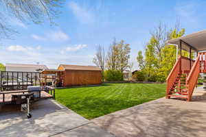 View of yard with a storage unit, an outbuilding, fence, a patio area, and stairs