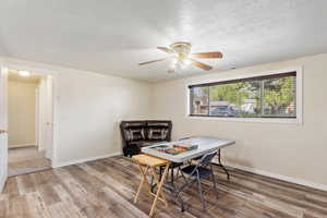Dining room with a textured ceiling, wood finished floors, visible vents, and a ceiling fan