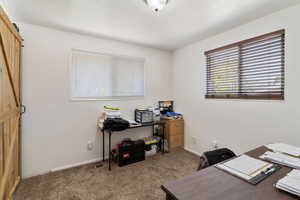Office space with baseboards, carpet, and a barn door