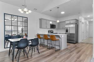 Kitchen featuring visible vents, a peninsula, gray cabinetry, and appliances with stainless steel finishes