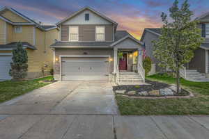 Traditional-style house with board and batten siding, an attached garage, and driveway